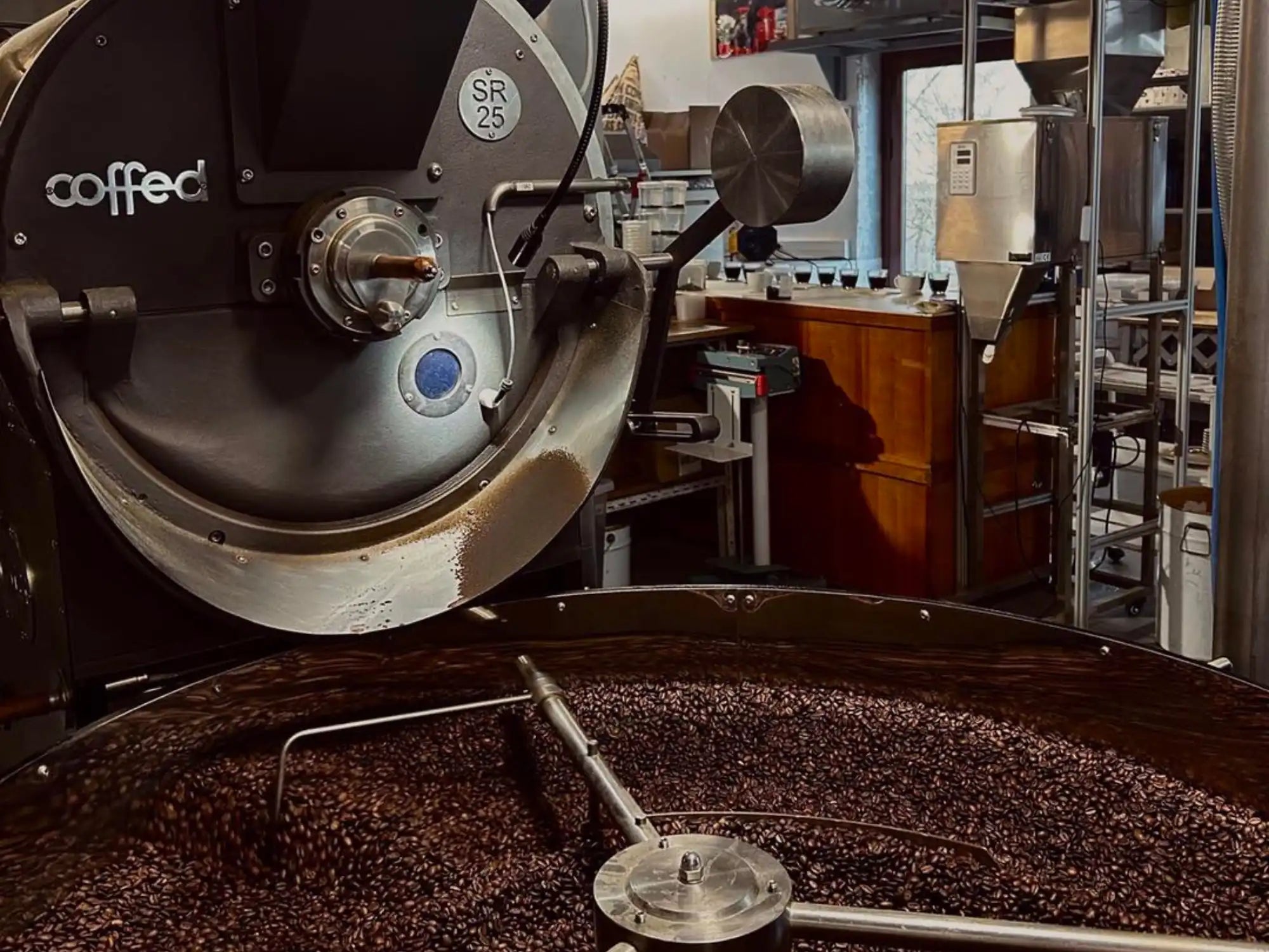 Torréfacteur dans l’atelier avec réservoir rempli de grains de café fraîchement torréfiés